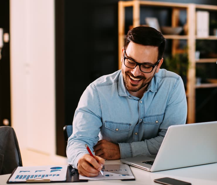 Man in front of laptop screen, taking notes